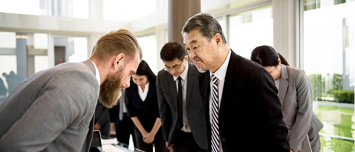 Man gives a Japanese greeting to a group of Japanese people.