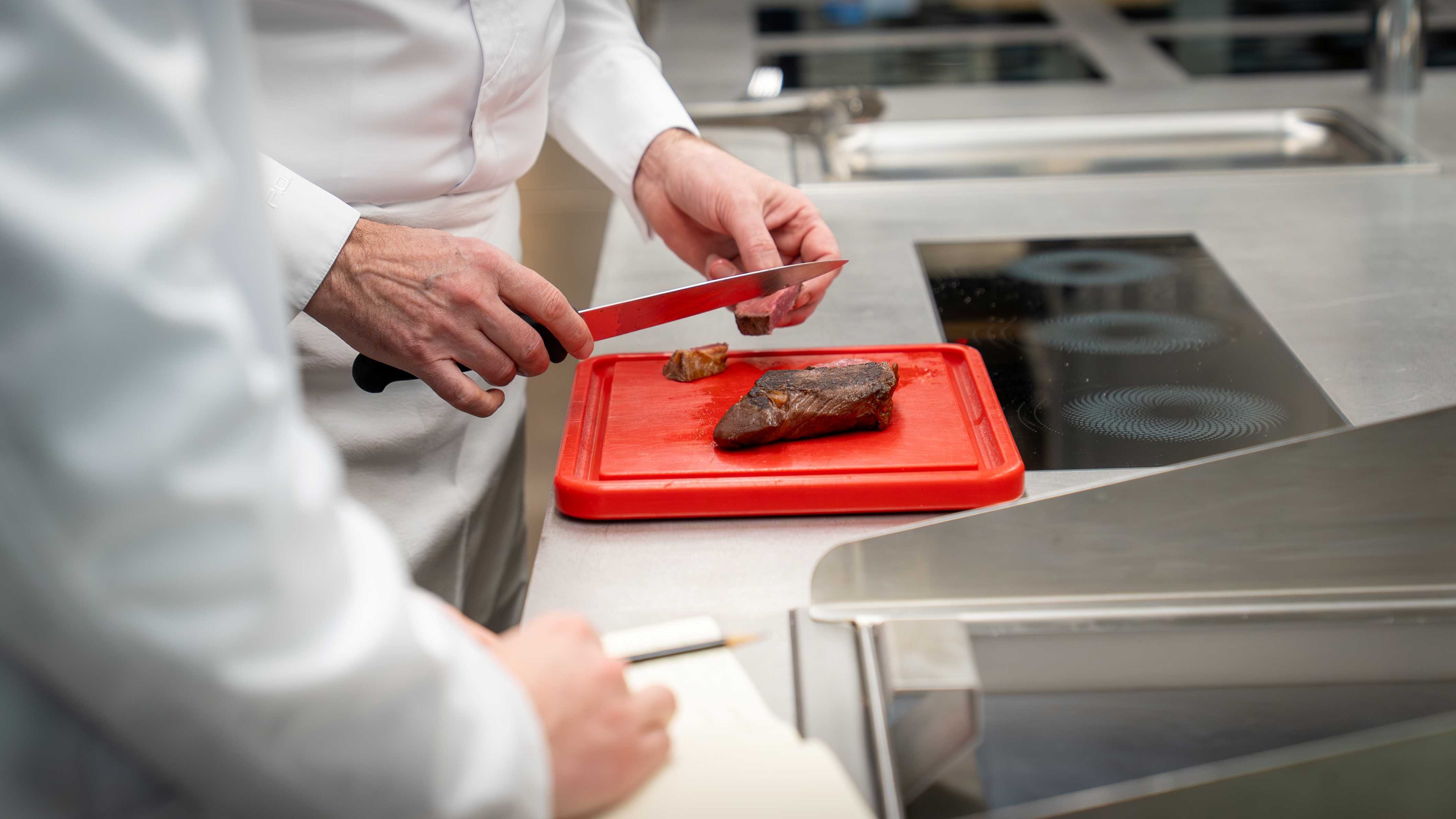 Chef Patrick Ogheard cutting meat with a chefs knife