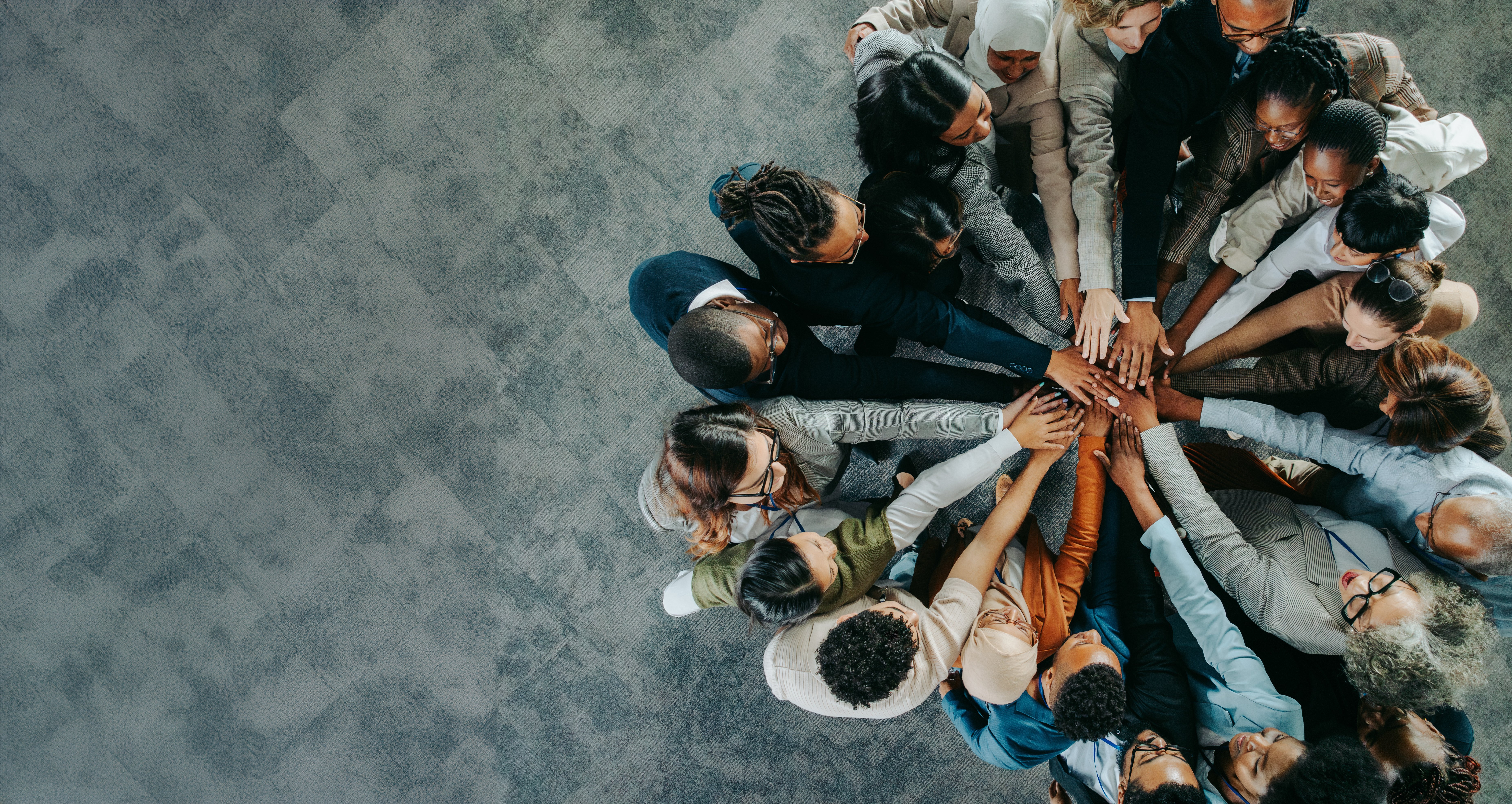 A group of people standing in a circle with their hands stacked together, representing good conditions for collaboration.