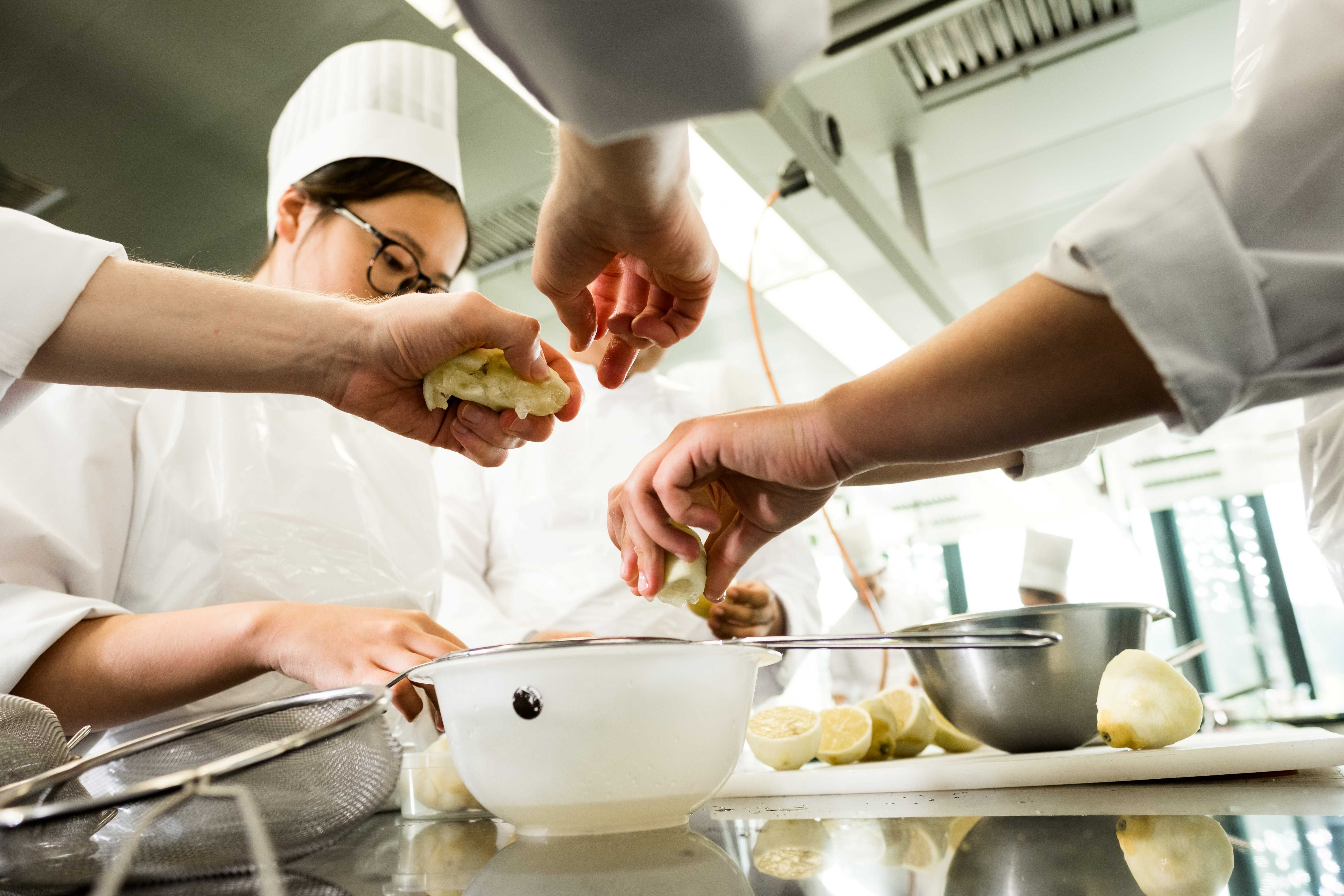 Students working with utensils in a professional kitchen at EHL Lausanne