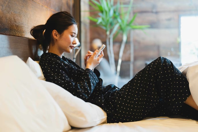 A woman sitting in the bed of a smart hotel room