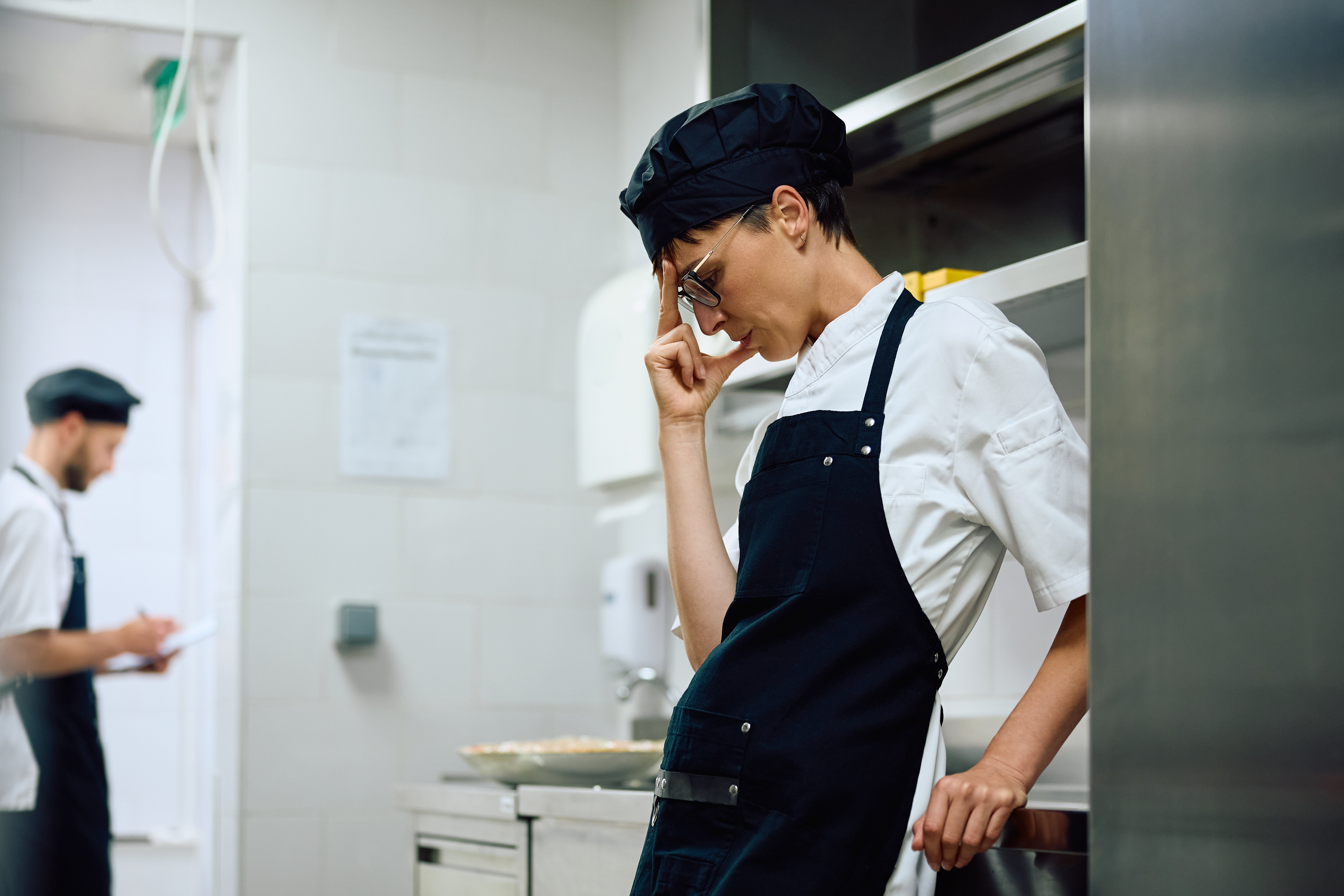 stressed restaurant employee standing in kitchen