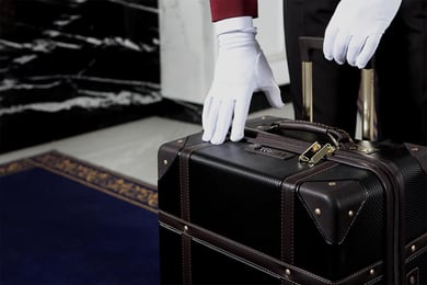 White glove of a bell hop picking up luggage as part of the luxury experience