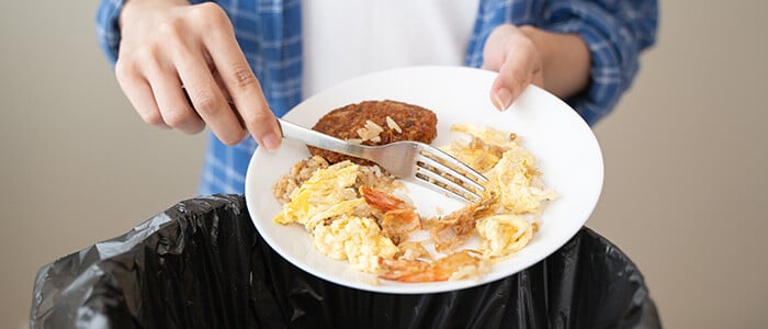 A person displays a plate filled with food, showcasing a commitment to reducing waste in culinary habits