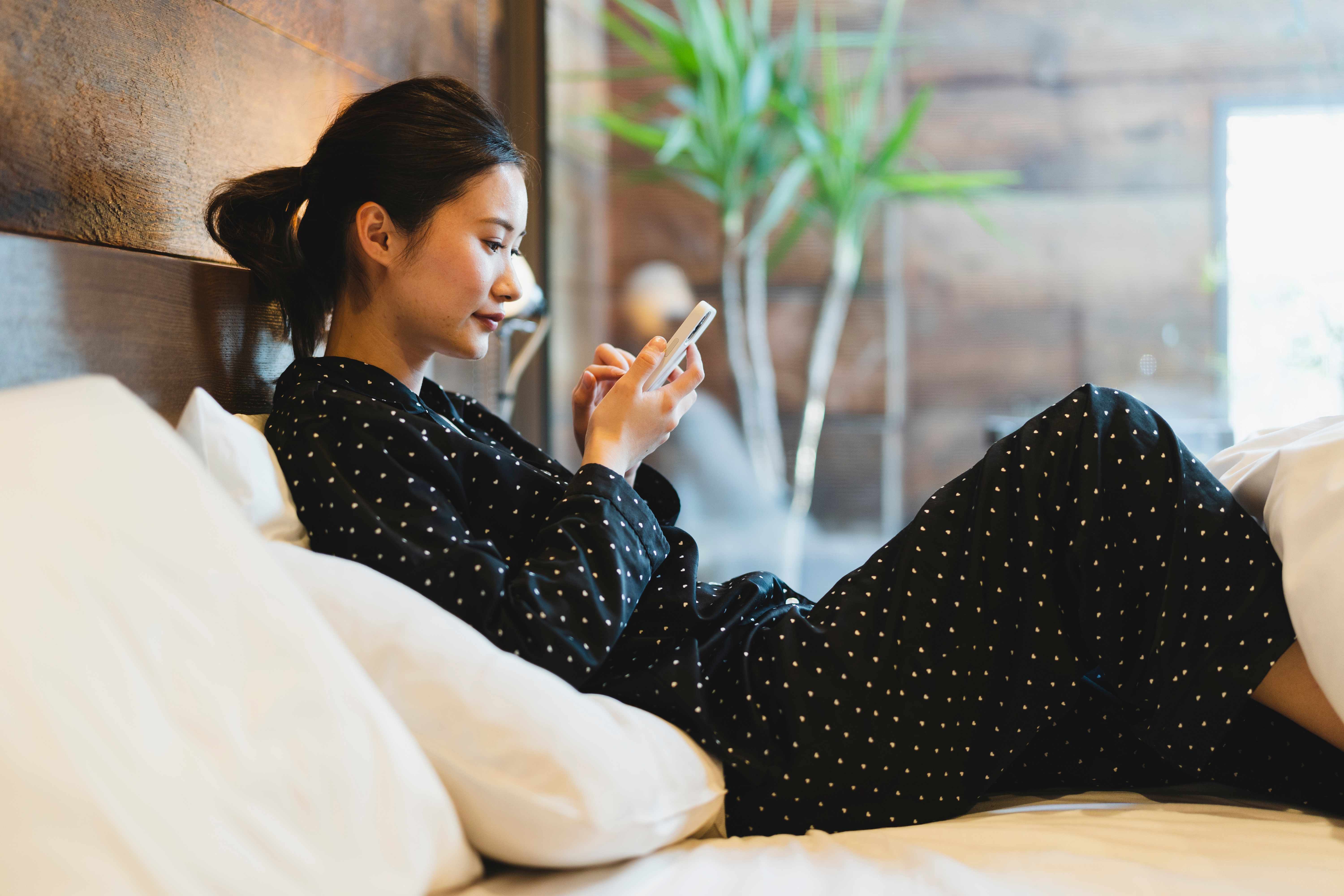 A woman sitting in the bed of a smart hotel room