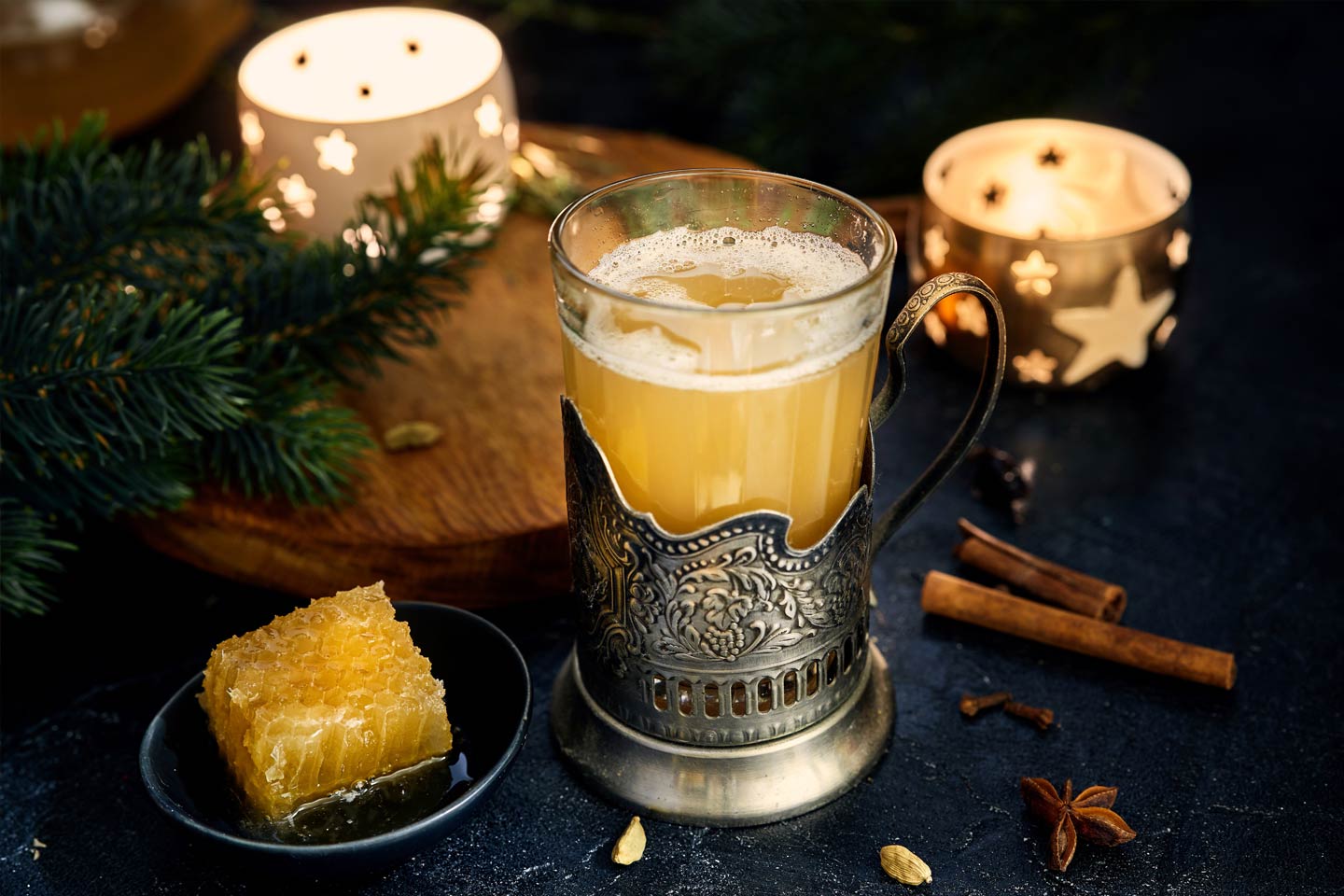 a glass of sbiten, cinamon and candles to make it Christmas